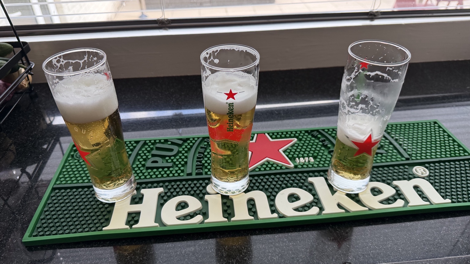 Drie glazen vers getapt Heineken-bier op een barmat