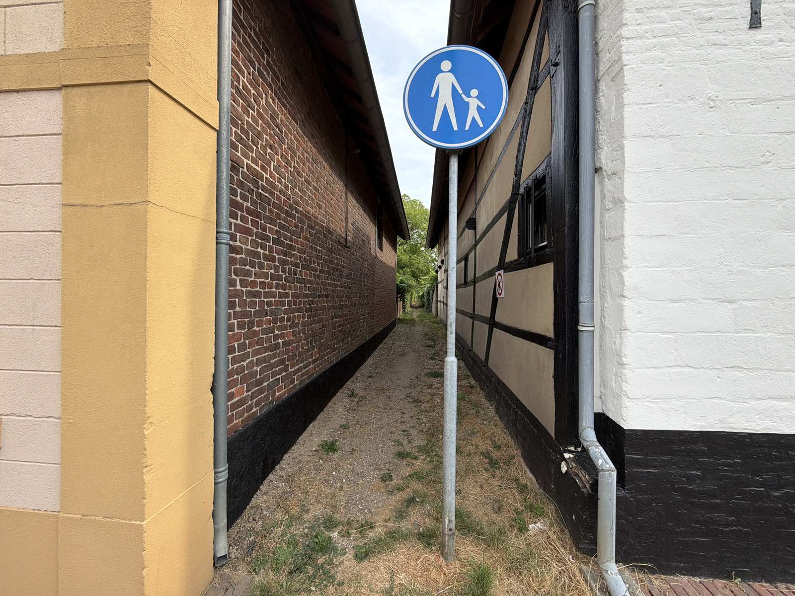 Smal voetpad tussen oude bebouwing in Genhout